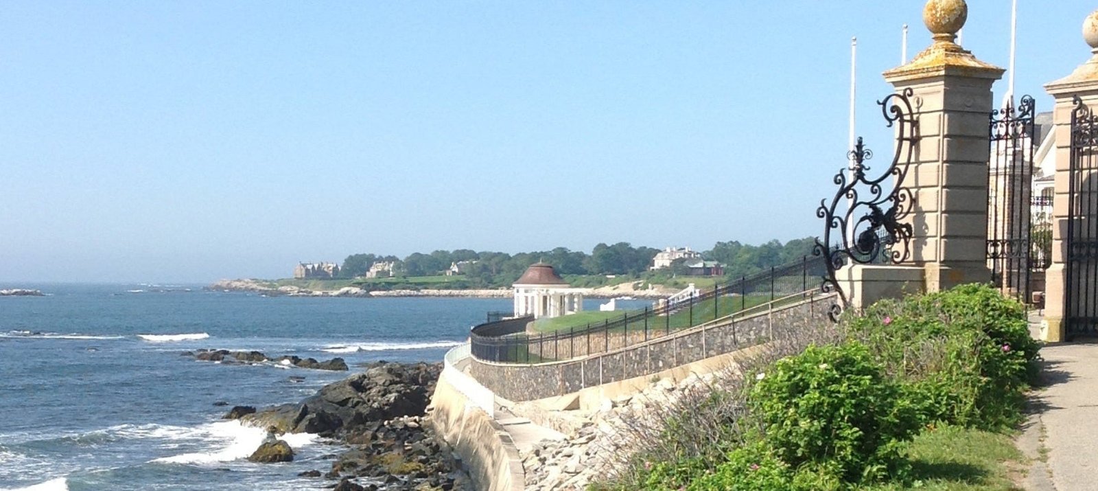 Pathway along a coastal area with ocean view and decorative columns.